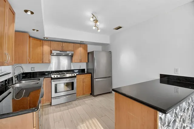 a kitchen with stainless steel appliances granite countertop a stove a sink and a refrigerator