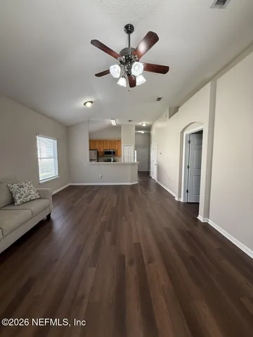 a view of an empty room with wooden floor and a window