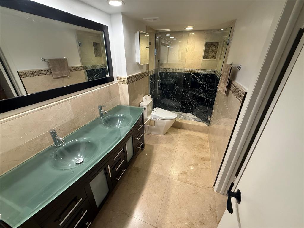 19428 Northeast 26th Avenue, Unit 103 Miami, FL 33180 - Photo 25 of 65 a bathroom with a double vanity sink and a mirror