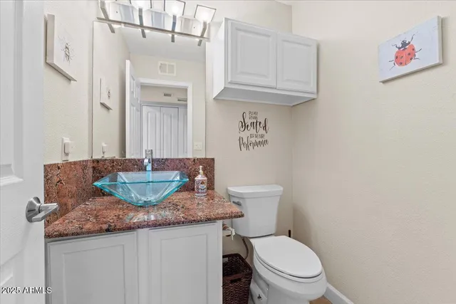 a bathroom with a granite countertop toilet sink and mirror