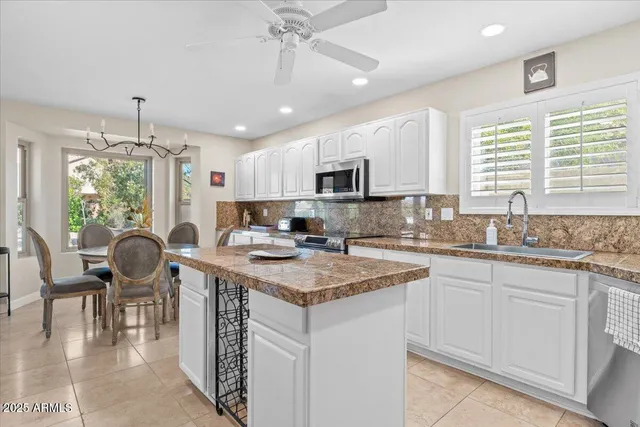 a kitchen with kitchen island granite countertop a sink cabinets and window