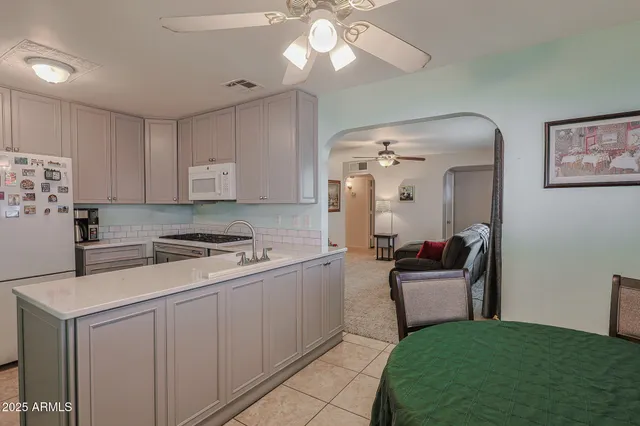 a kitchen with a stove a refrigerator and chairs
