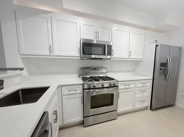 a kitchen with white cabinets and stainless steel appliances