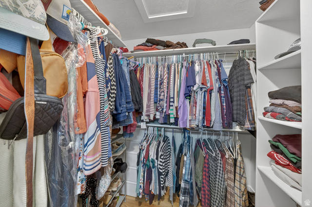 7872 Farm House Lane Midvale, UT 84047 - Photo 21 of 39 Primary Walk-in closet featuring white built-in shelving, multiple hanging rods, and a ceiling light fixture