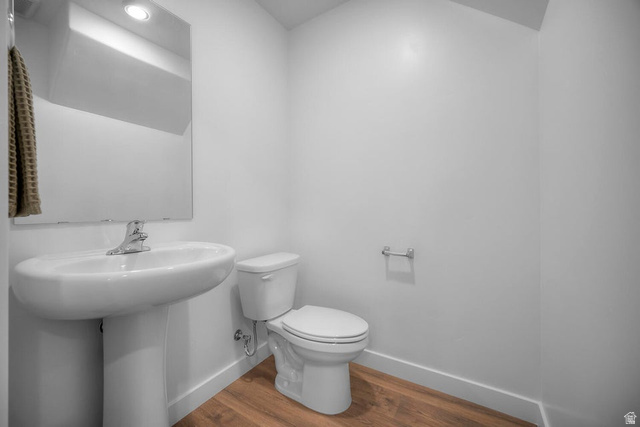 2216 Wolverine Way Washington, UT 84780 - Photo 12 of 29 Bathroom featuring a pedestal sink, a toilet, wood-finish flooring, and a wall-mounted mirror