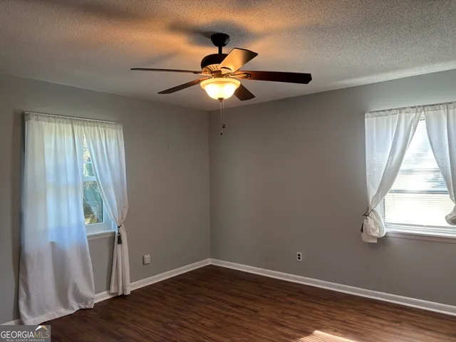 a view of empty room with wooden floor and fan