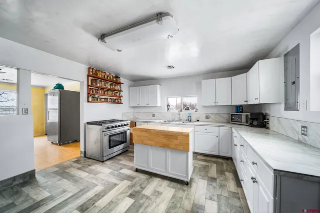 a large kitchen with stainless steel appliances granite countertop a stove refrigerator and cabinets