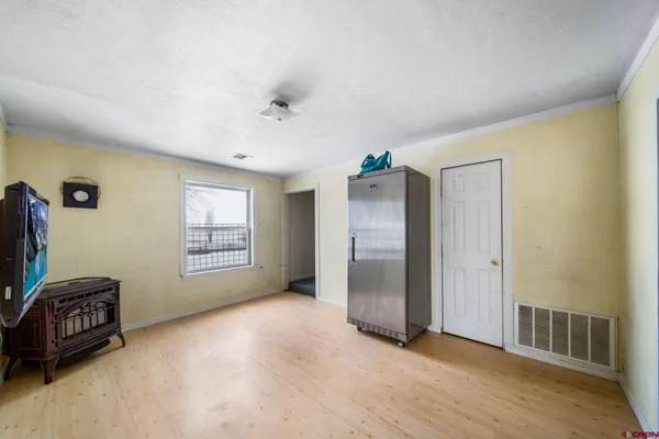 a view of an empty room with a window and a kitchen