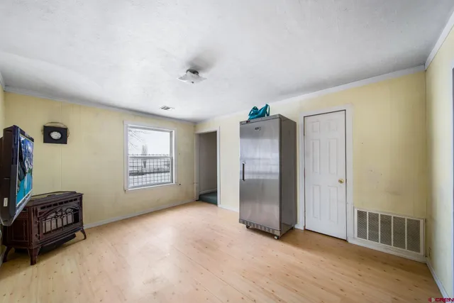 a view of an empty room with a window and a kitchen