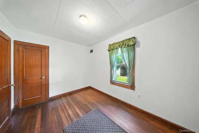 an empty room with wooden floor closet and windows
