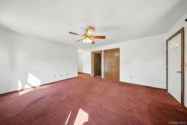 a view of a big room with carpet and chandelier fan