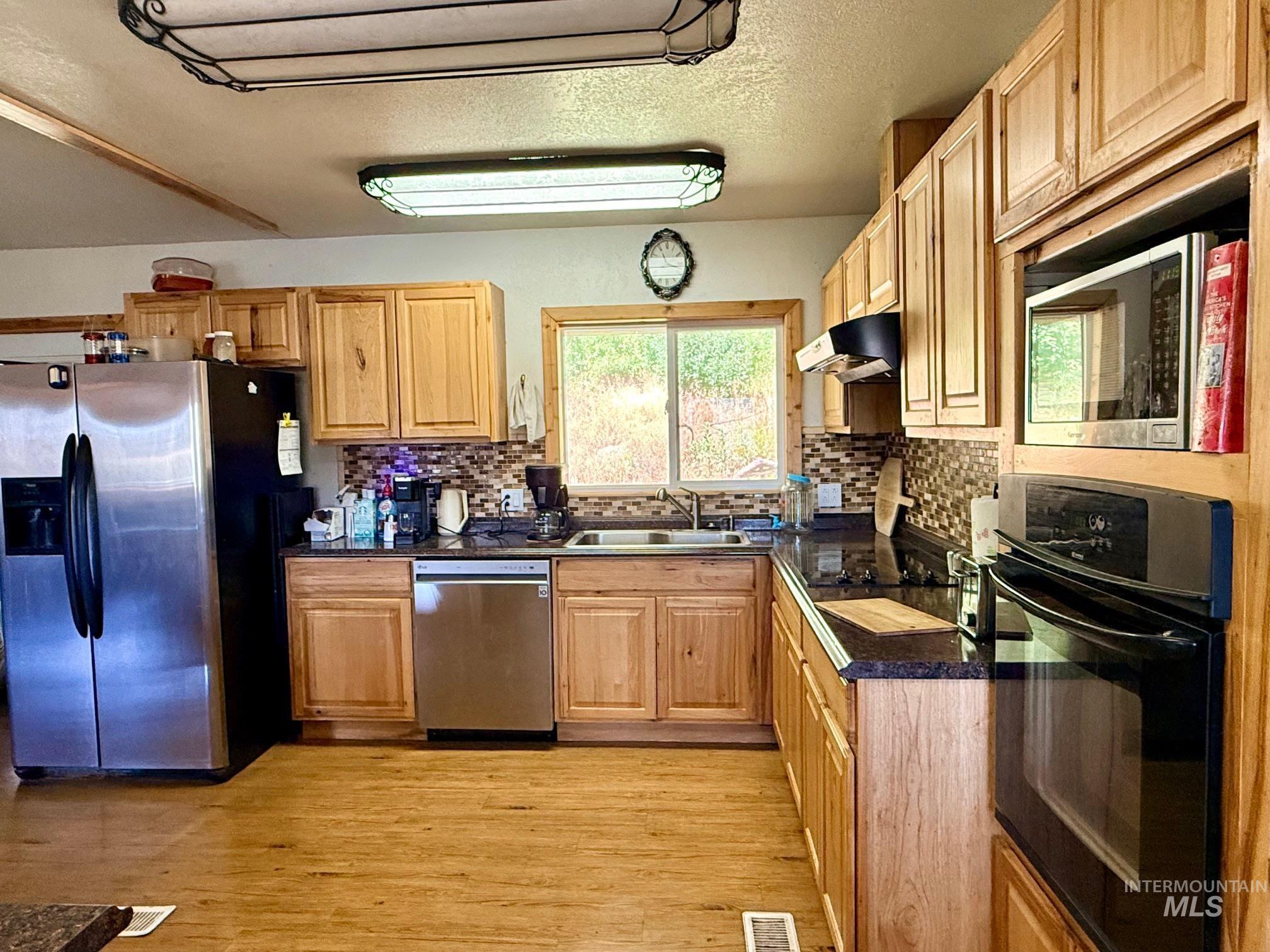 35322 River Road Lenore, ID 83541 - Photo 12 of 42 Kitchen featuring wood-finish cabinetry, dark countertops, and a mosaic tile backsplash