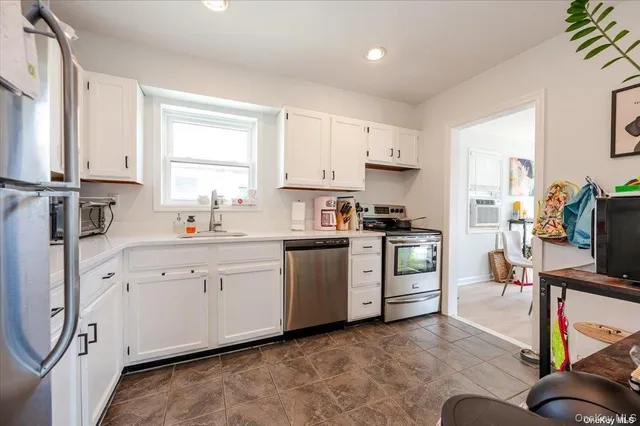 a kitchen with granite countertop a sink cabinets stainless steel appliances and a window
