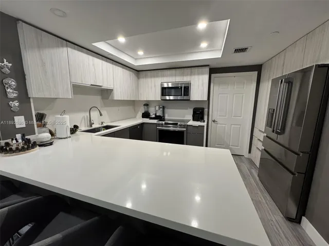 a large kitchen with stainless steel appliances a refrigerator a sink a stove a microwave and cabinets