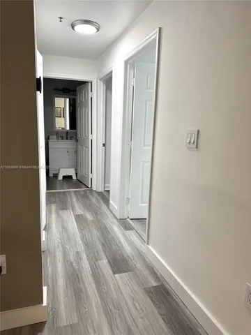 a view of a hallway with wooden floor and a bathroom