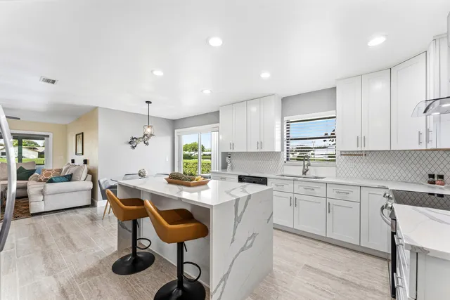 a kitchen with stainless steel appliances kitchen island granite countertop a table chairs sink and cabinets