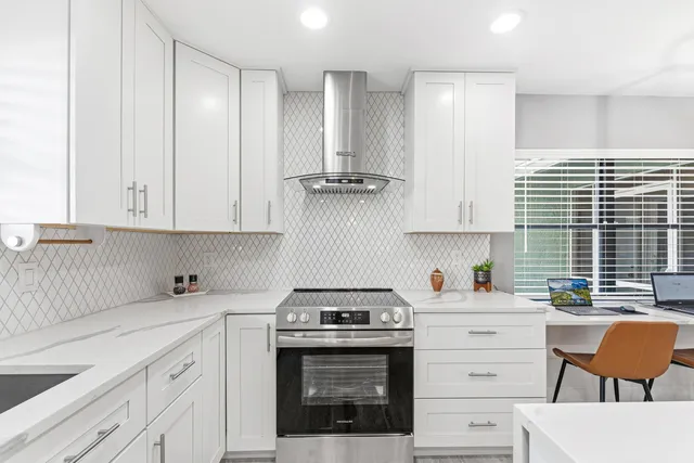 a kitchen with stainless steel appliances white cabinets and a stove top oven