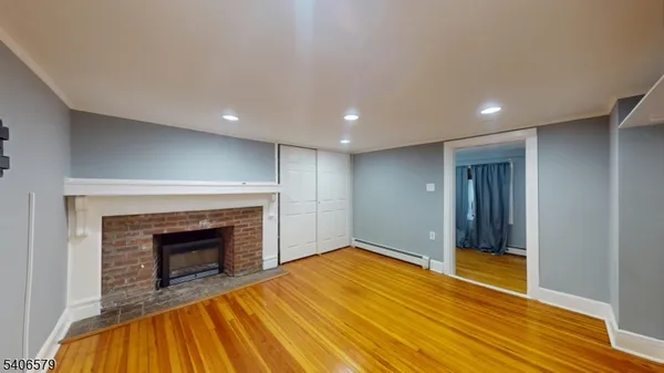 a view of empty room with wooden floor and fireplace