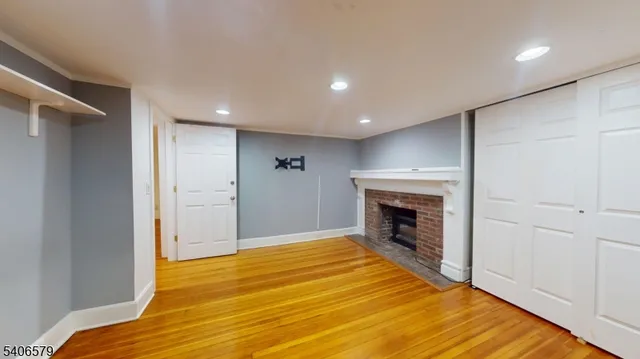 a view of an empty room with wooden floor fireplace and a window