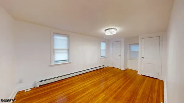 a view of empty room with window and wooden floor