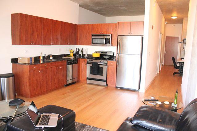 235 West Van Buren Street, Unit 3721 Chicago, IL 60607 - Photo 9 of 17 a kitchen with stainless steel appliances granite countertop a refrigerator a stove and a sink with wooden cabinets