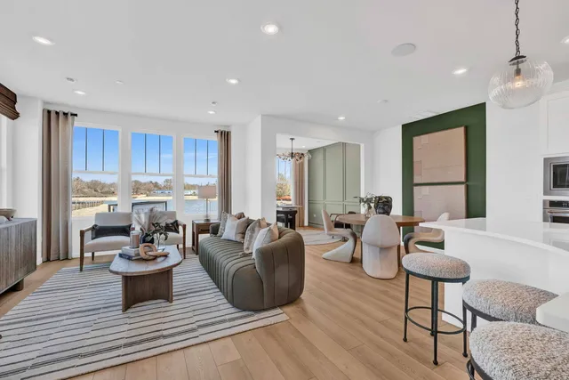 a living room with furniture large window and wooden floor