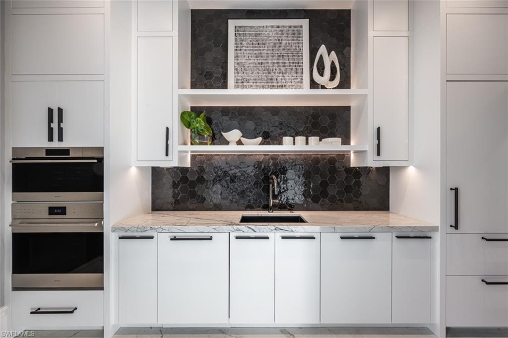 405 Neapolitan Way Naples, FL 34103 - Photo 16 of 50 a kitchen with white cabinets and black appliances