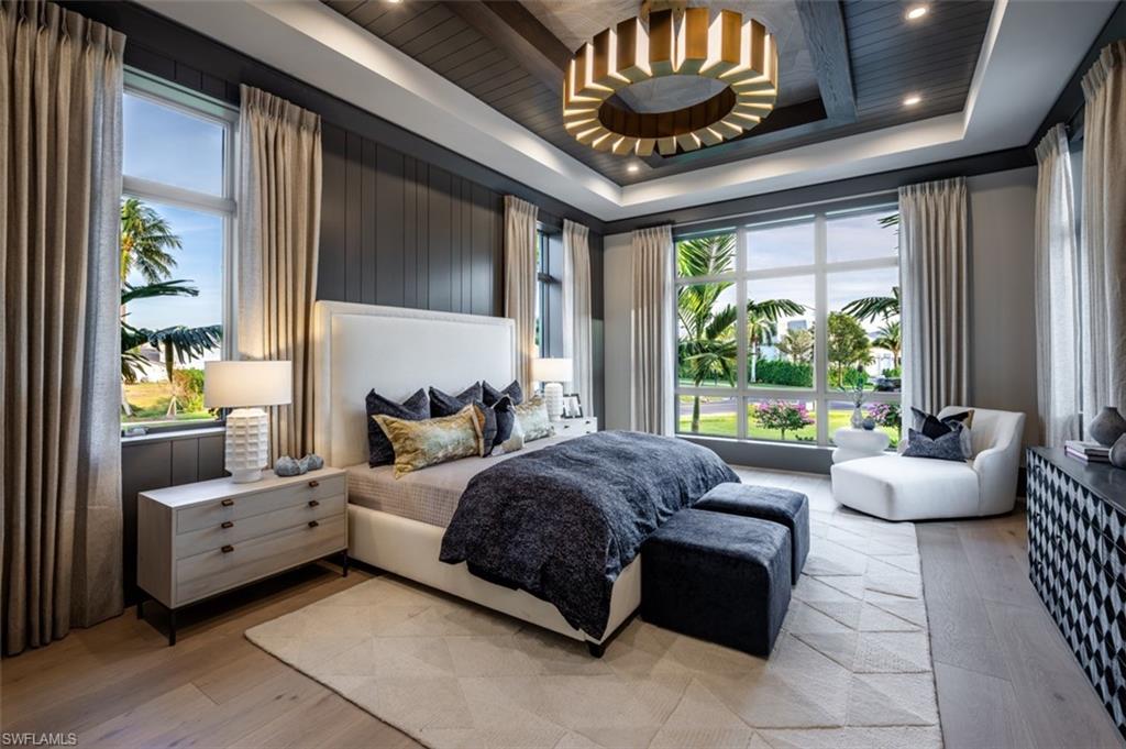 405 Neapolitan Way Naples, FL 34103 - Photo 24 of 50 a spacious bedroom with a bed and a chandelier