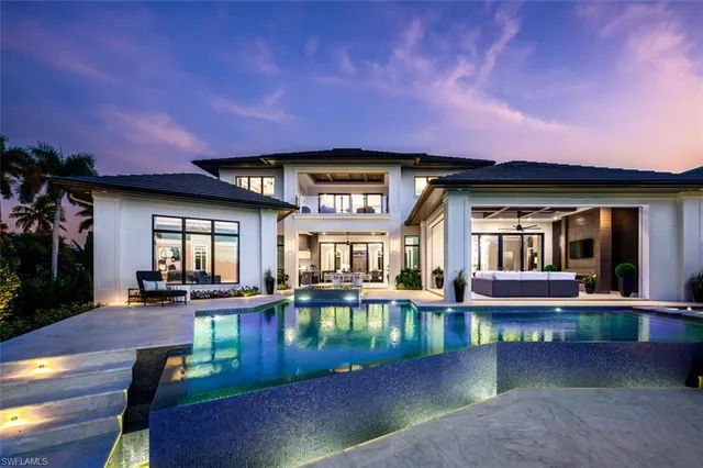 a front view of a house with swimming pool and table chairs