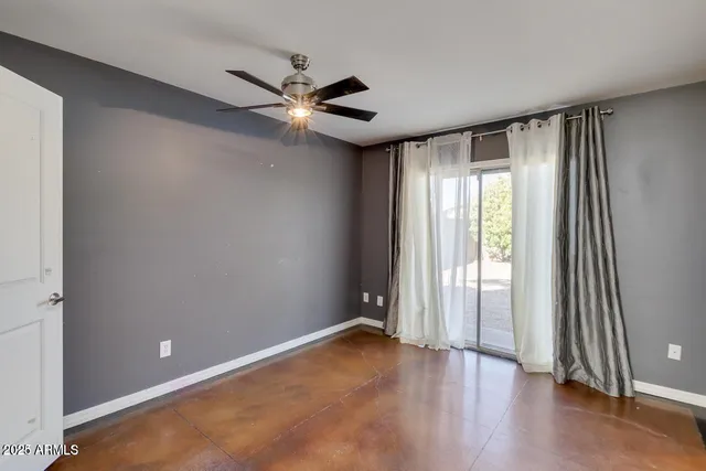 an empty room with wooden floor fan and windows