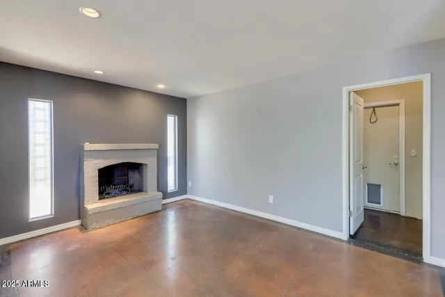 a view of an empty room with window and fire place