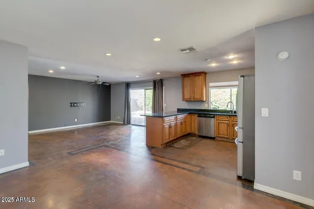 a view of an empty room with kitchen and window