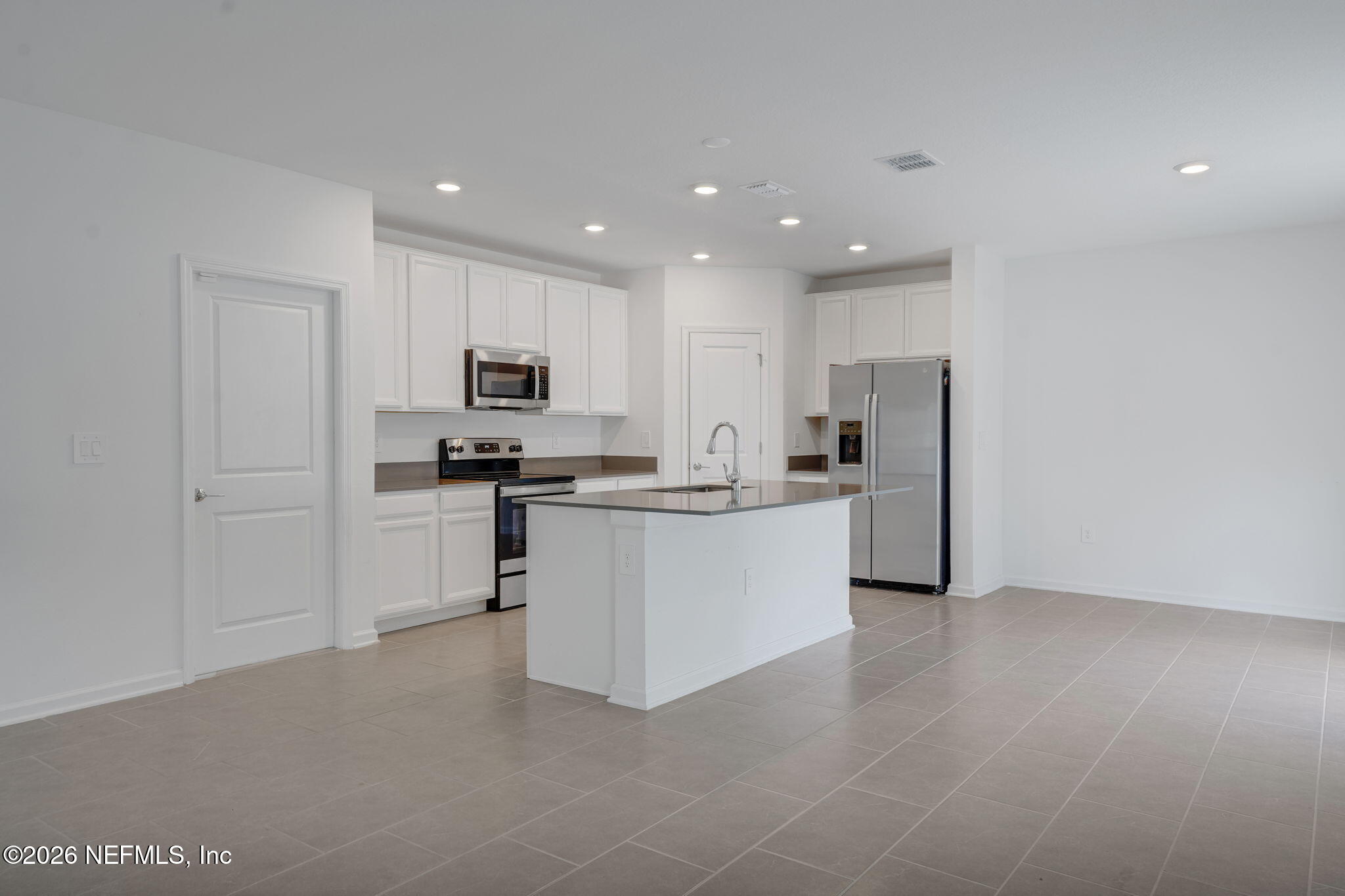 1214 Fury Street Davenport, FL 33837 - Photo 6 of 37 a kitchen with white cabinets and stainless steel appliances