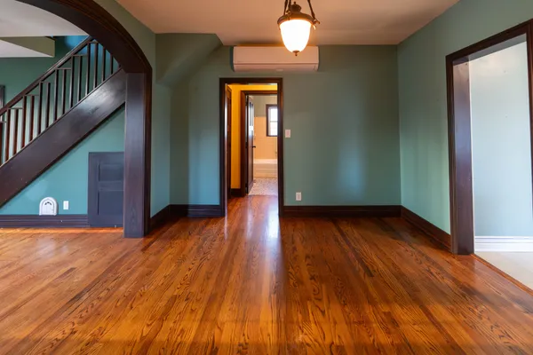 a view of a livingroom with wooden floor stairs and a chandelier
