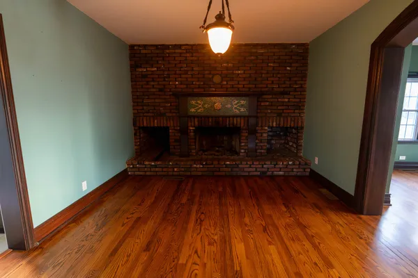 a view of an empty room with wooden floor and windows