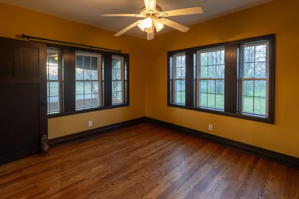 a view of an empty room with window and wooden floor