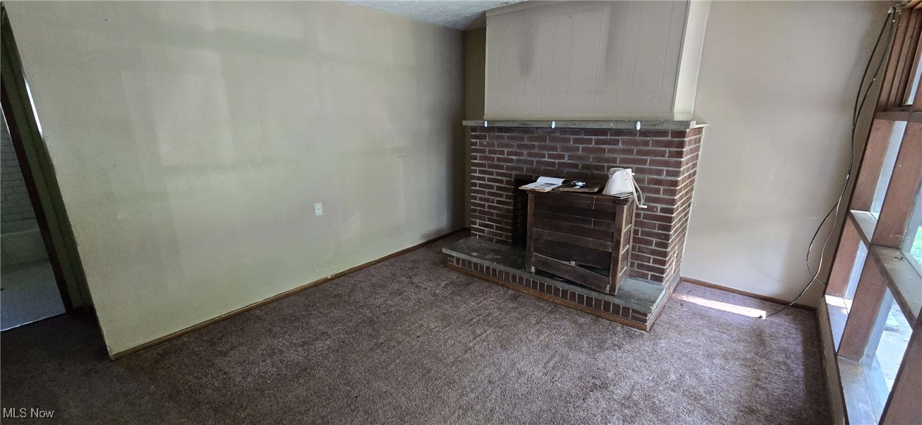 1943 Clyde Road Madison, OH 44057 - Photo 15 of 16 Unfurnished living room featuring carpet flooring, a fireplace, and a textured ceiling