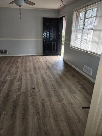 a view of an empty room with kitchen and window