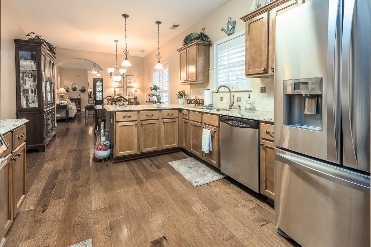 6031 Grayce Drive Bartlett, TN 38134 - Photo 10 of 31 a kitchen with stainless steel appliances granite countertop a stove a sink and white cabinets with wooden floor