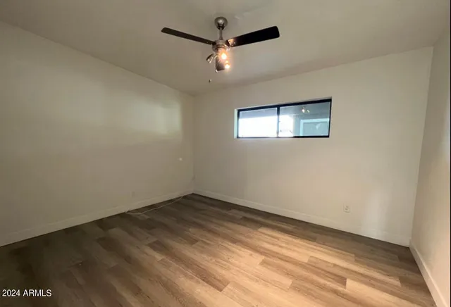 an empty room with a ceiling fan and window