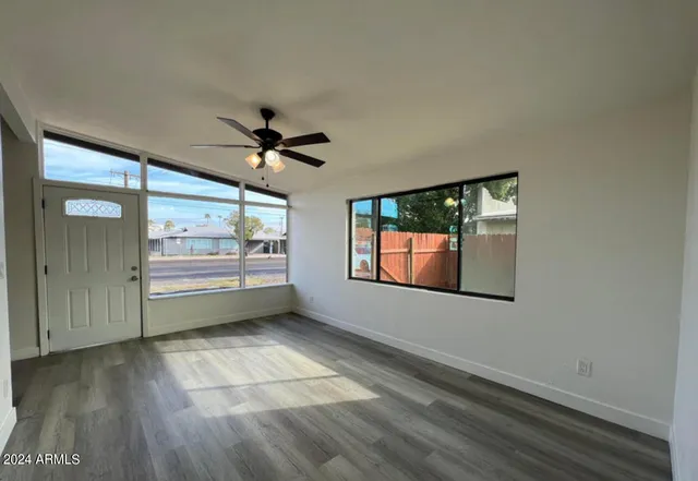 an empty room with windows and ceiling fan