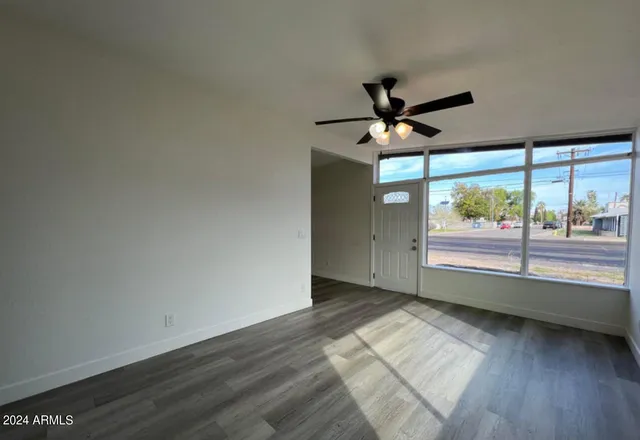 an empty room with wooden floor and windows