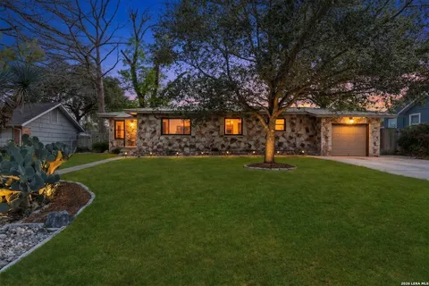 a front view of a house with a garden and trees