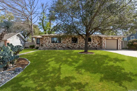 a view of a house with a big yard and large tree