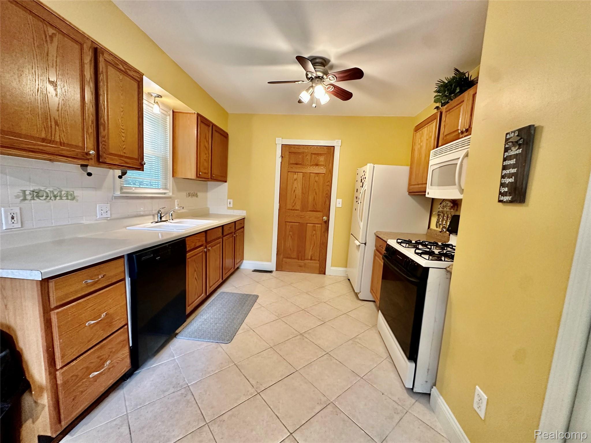 3404 Rockhaven Avenue Rochester, MI 48309 - Photo 6 of 19 Kitchen featuring wood cabinetry, light-toned countertops, a white tile backsplash, and ceramic tile flooring