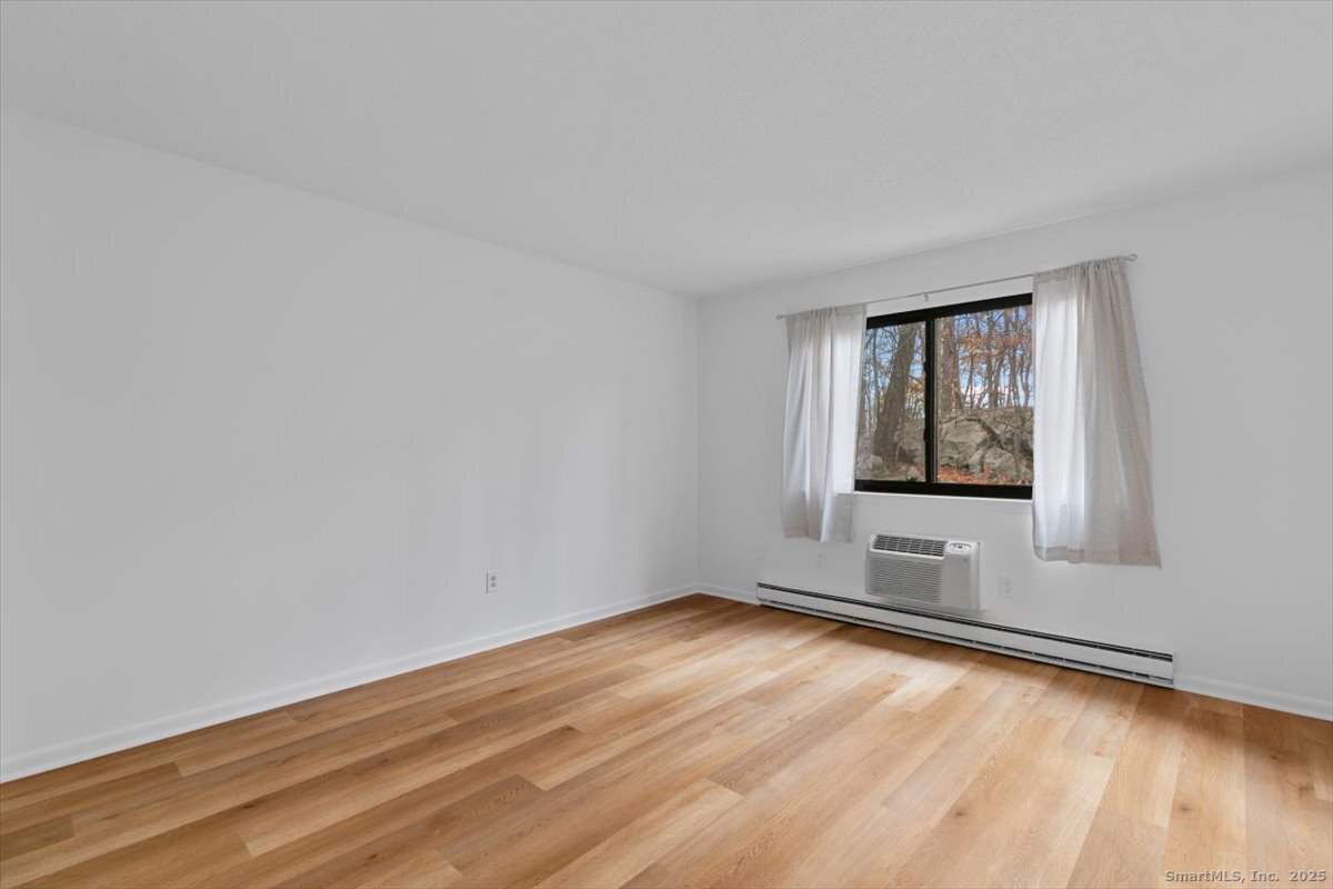 2998 Madison Avenue, Unit C Bridgeport, CT 06606 - Photo 17 of 24 a view of an empty room with wooden floor and a window