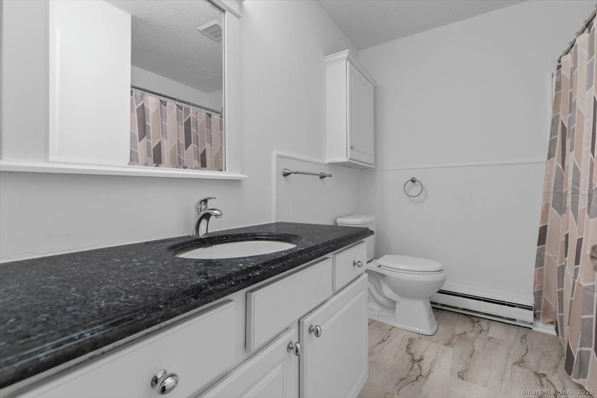 2998 Madison Avenue, Unit C Bridgeport, CT 06606 - Photo 19 of 24 a bathroom with a granite countertop toilet sink and mirror