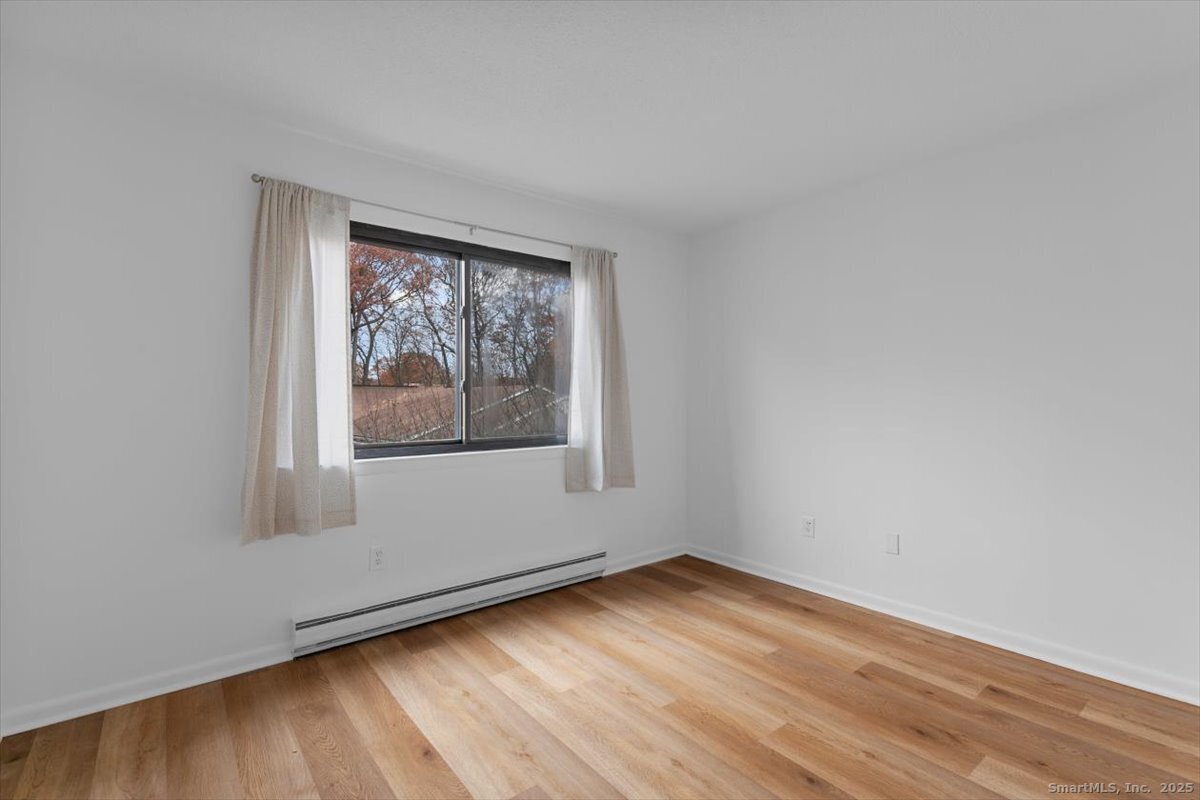 2998 Madison Avenue, Unit C Bridgeport, CT 06606 - Photo 22 of 24 an empty room with wooden floor and windows