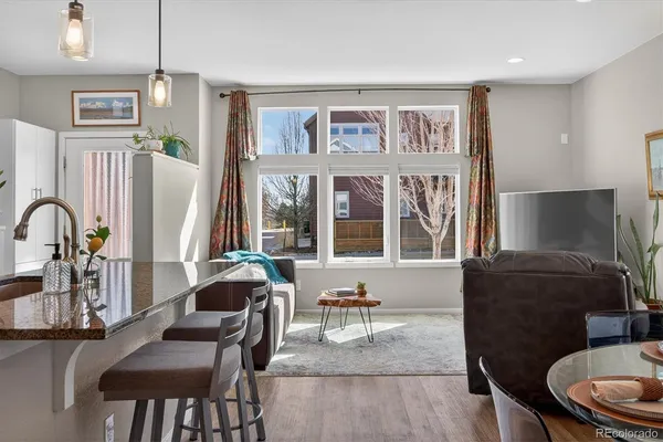 a living room with furniture two large window and wooden floor