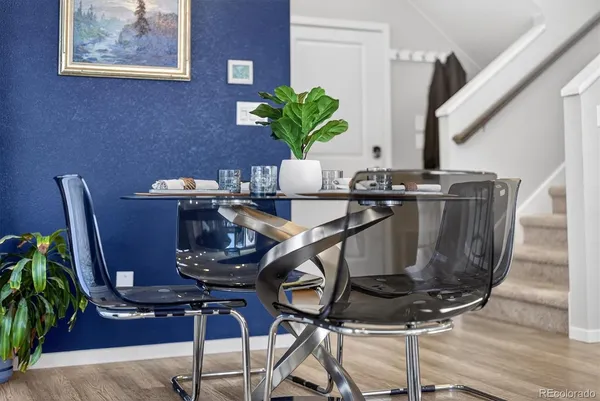 a table with a vase and flowers on it with table and chairs